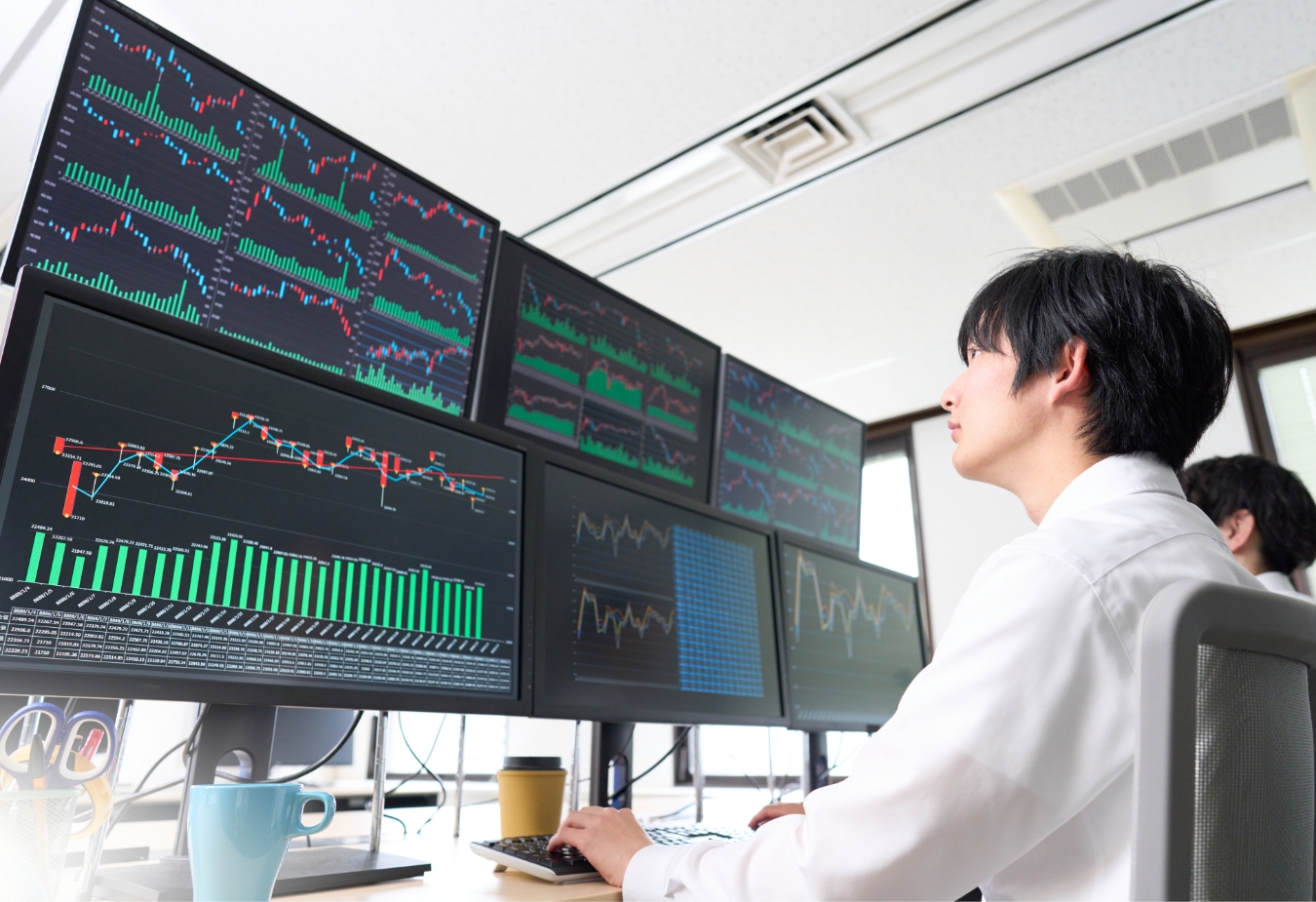 複数のモニターで株価グラフを見つめる男性