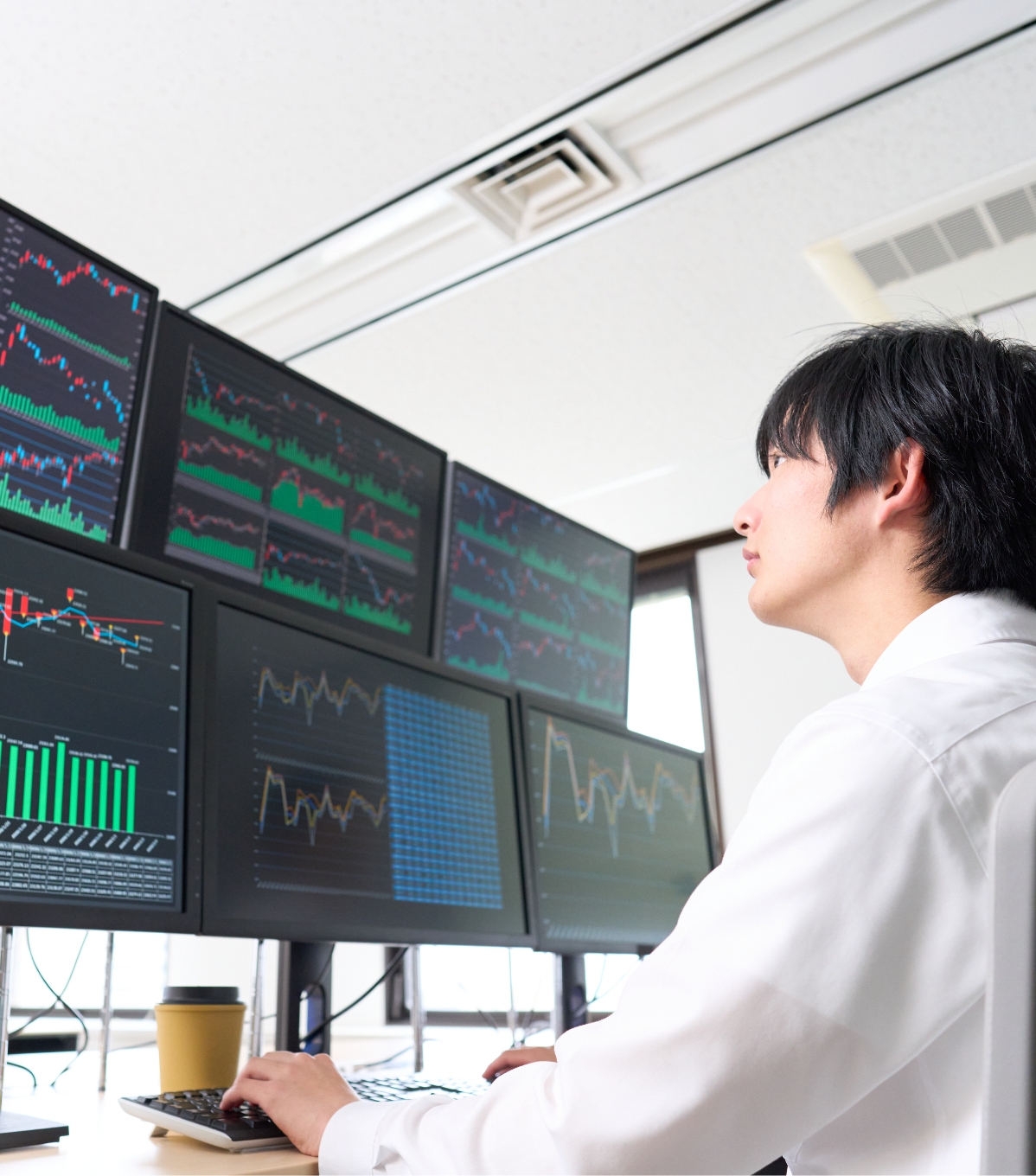 パソコンで株価グラフを見つめる男性
