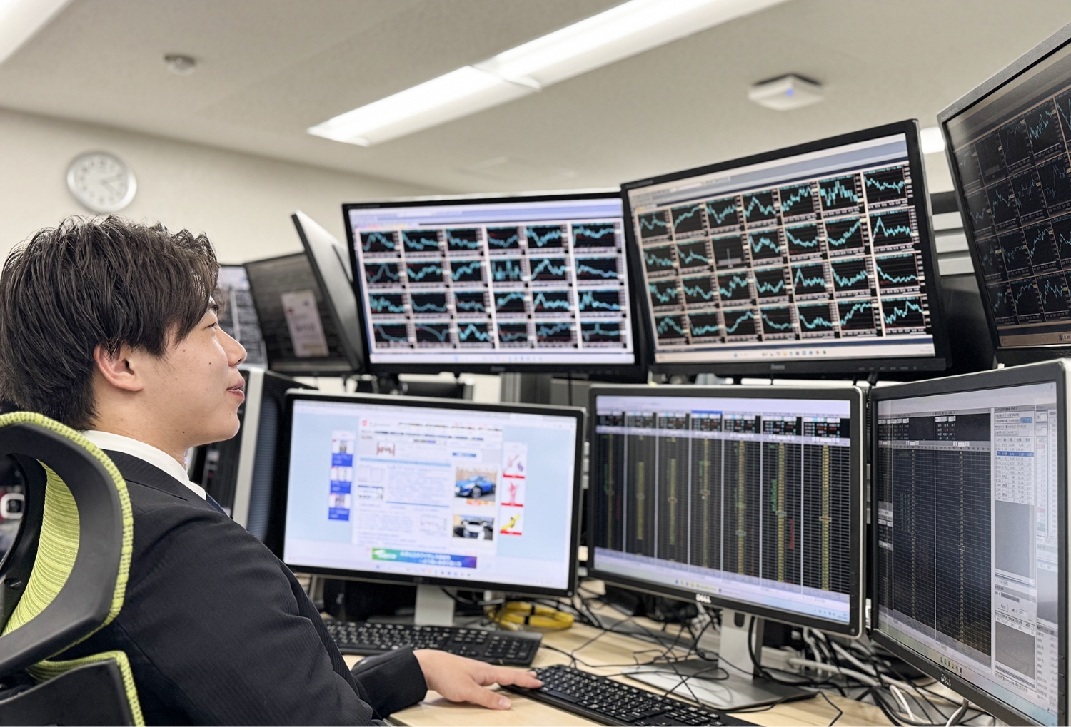複数のモニターで株価グラフを見つめる男性