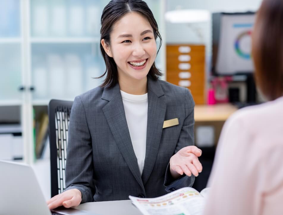 資料に手をむけて説明するスーツ姿の女性