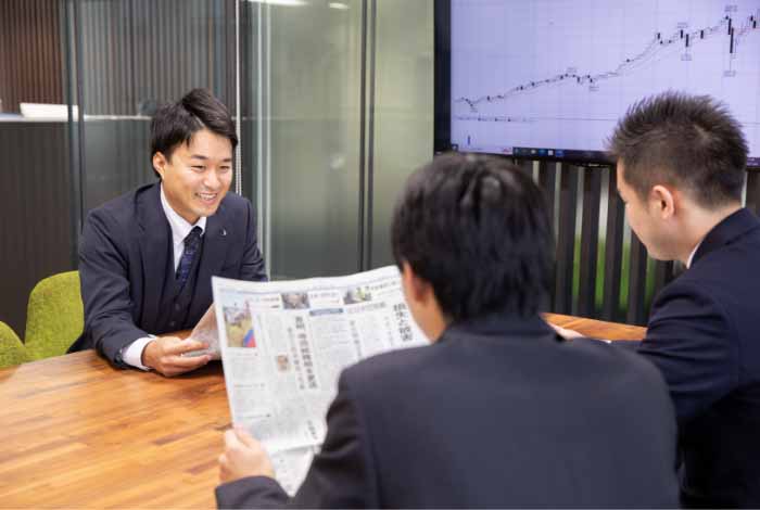 新聞紙を手にディスカッションする3人の男性