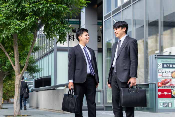 ビルの前で談笑するスーツ姿の男性2人