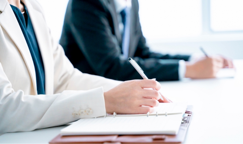 ペンでメモを取る女性の手元